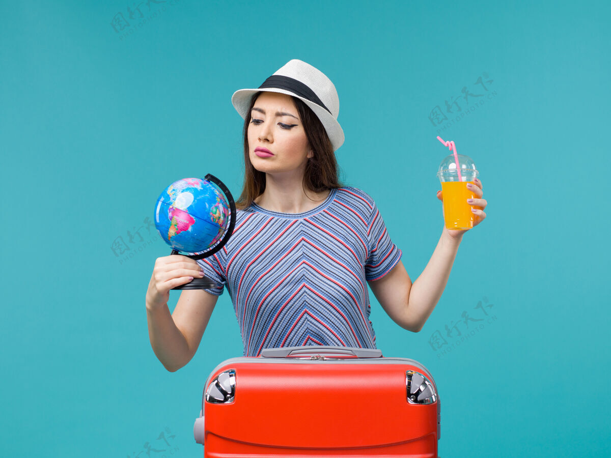 果汁前景度假妇女手持果汁和地球仪在蓝色的背景海上航行度假暑假旅行旅程运动成人