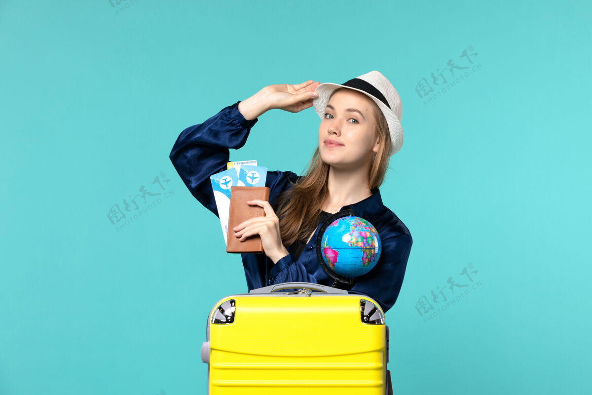 年轻的女人正面图年轻女子拿着钱包和机票上蓝色背景的飞机航行女子海上旅行度假美丽抱着肖像