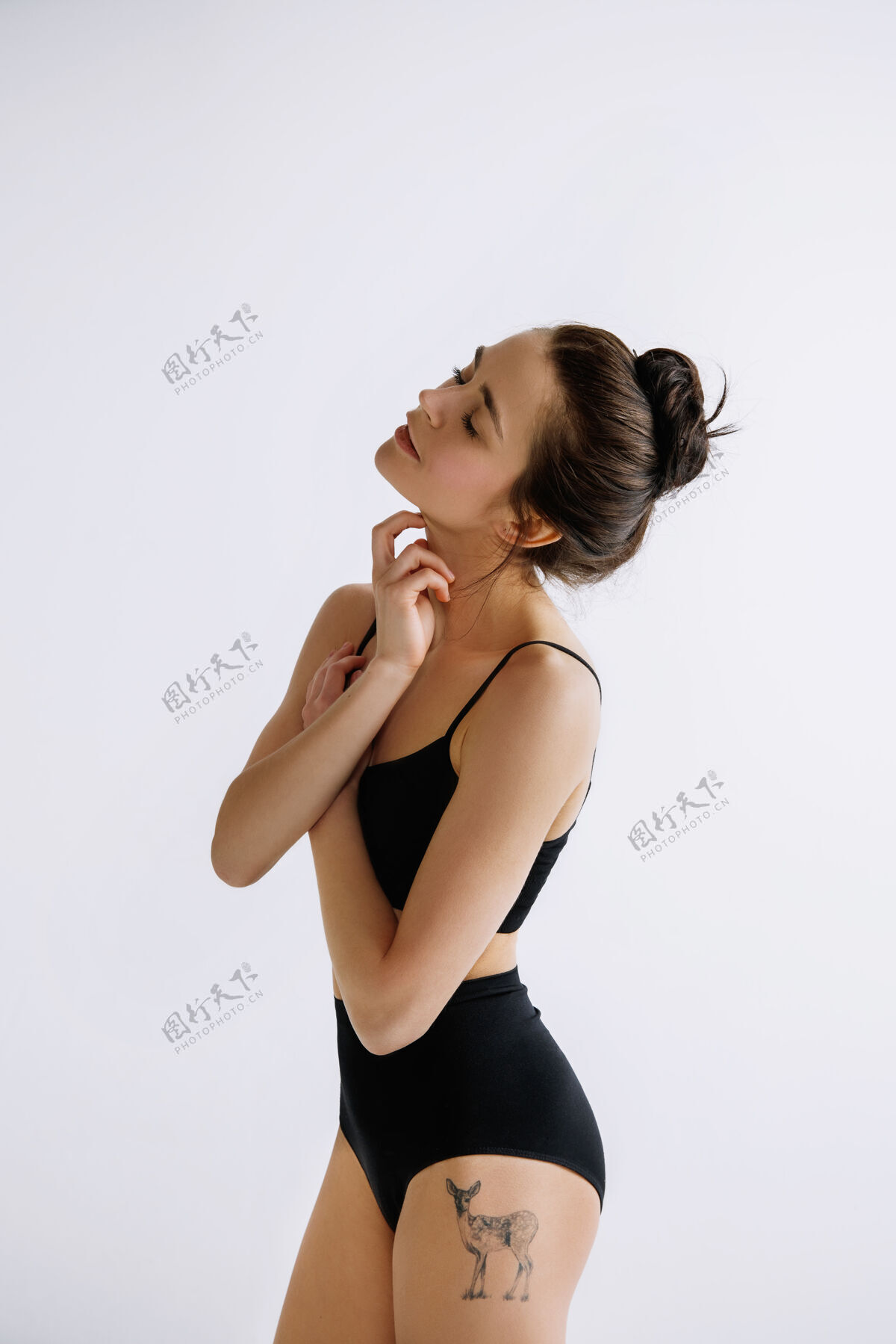 女人年轻的女芭蕾舞演员穿着黑色紧身衣 对着白色的工作室墙时尚明亮舞蹈