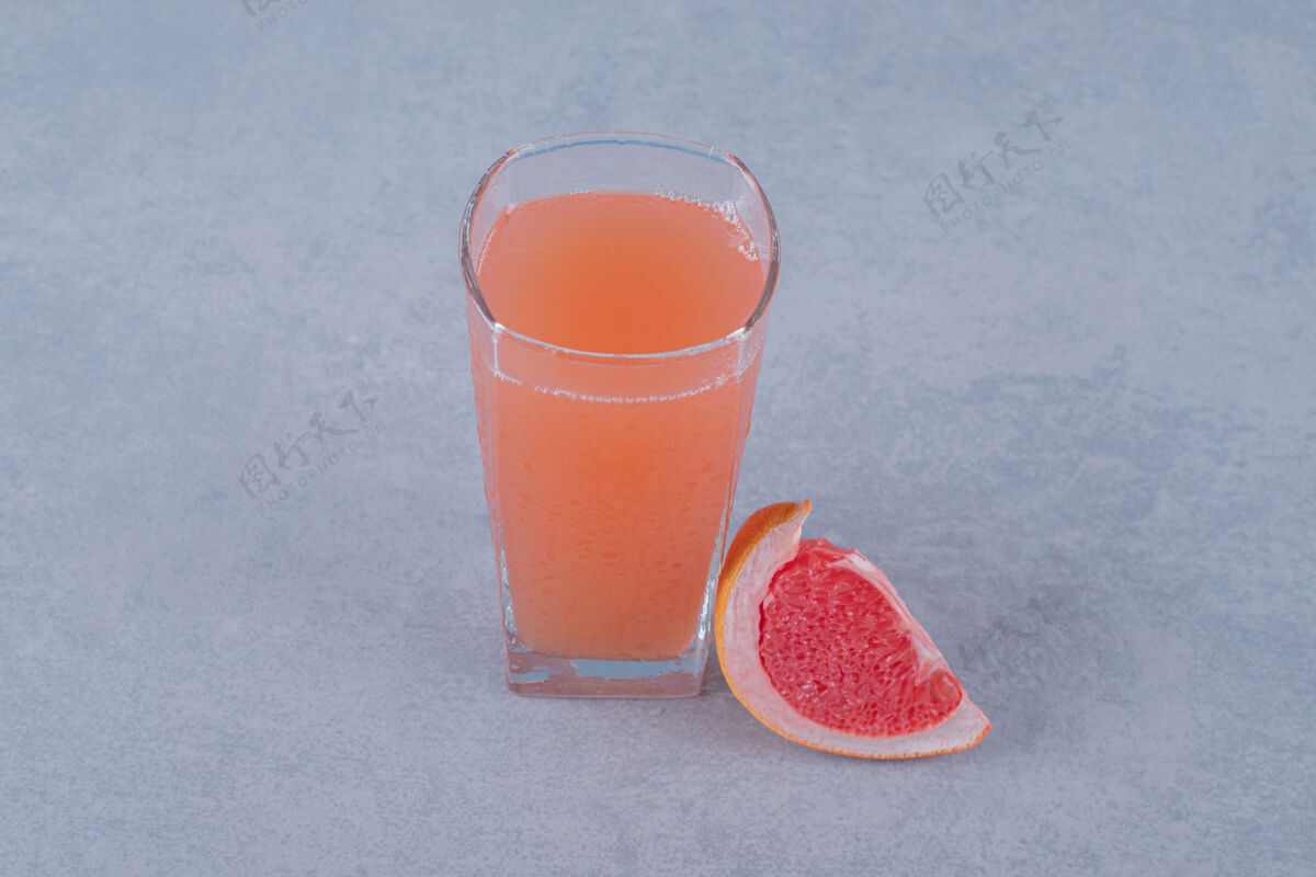 聚会新鲜的柚子汁和水果片放在灰色的表面上热带寒冷开胃酒