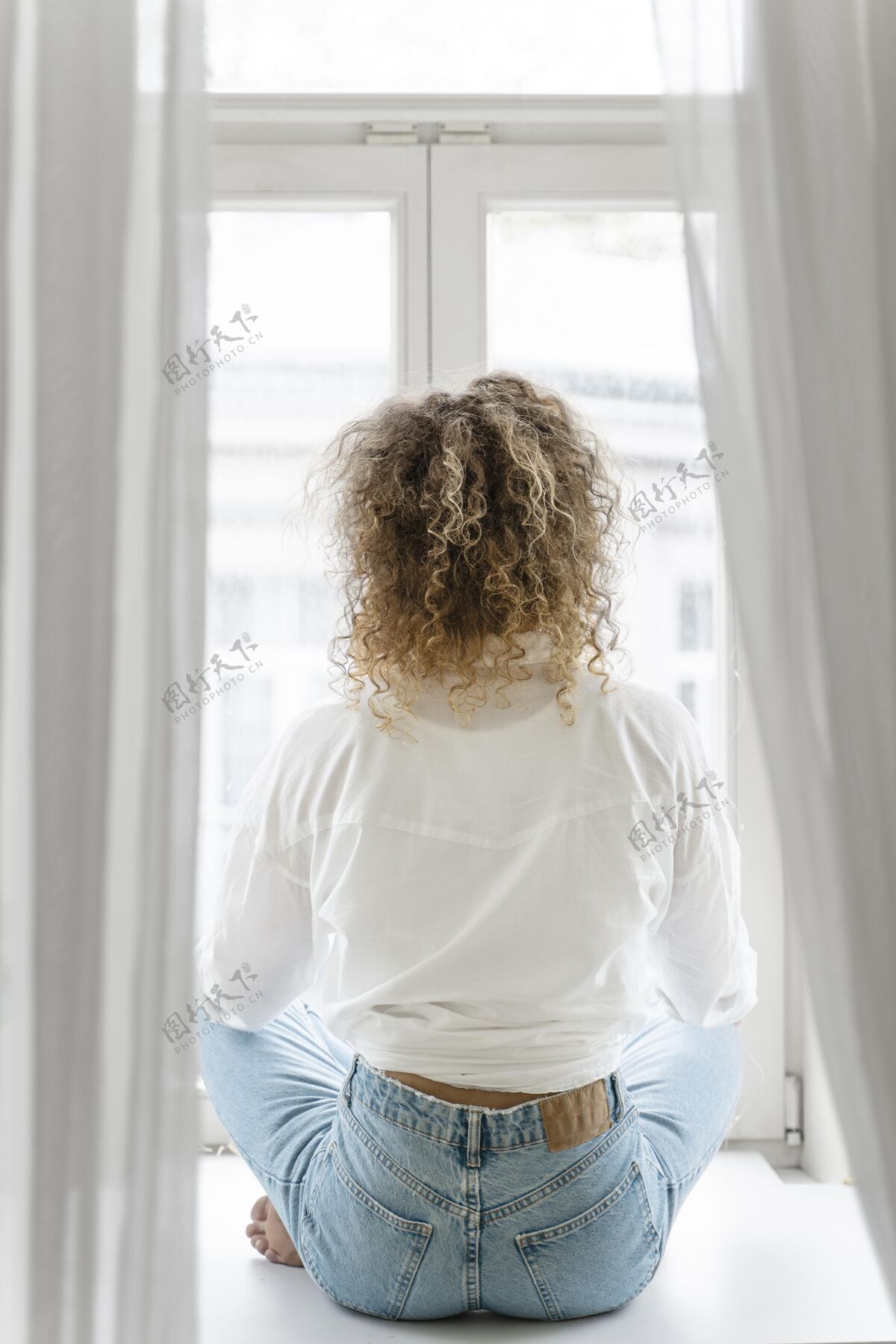窗户金发卷发女人在家放松的后视图室内活动宁静垂直
