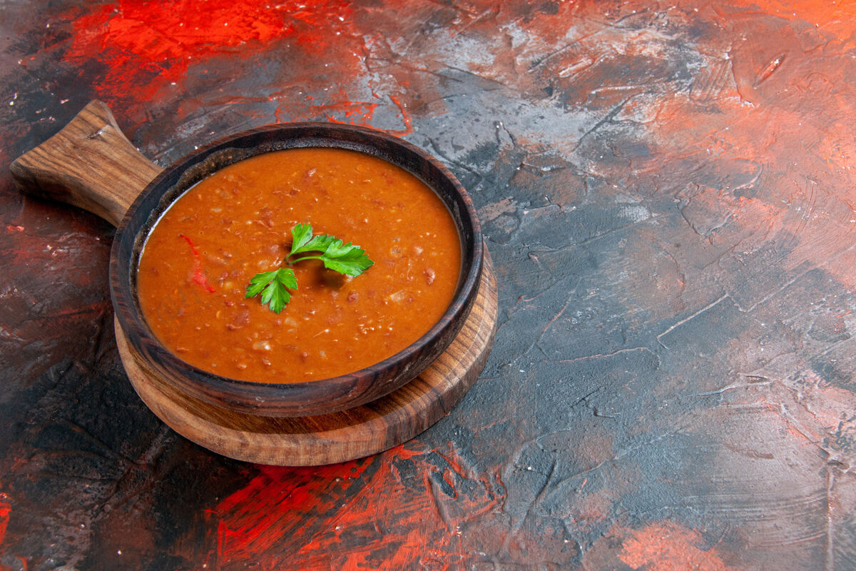 餐厅美味的西红柿汤放在一个棕色的砧板上 在一张五颜六色的桌子的右边西红柿汤壁板美味