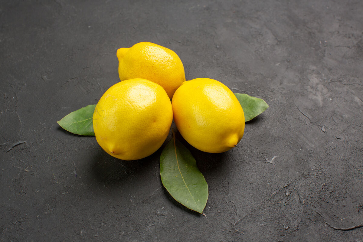 多汁前视图新鲜的酸柠檬和树叶在黑暗的背景水果柑橘饮食