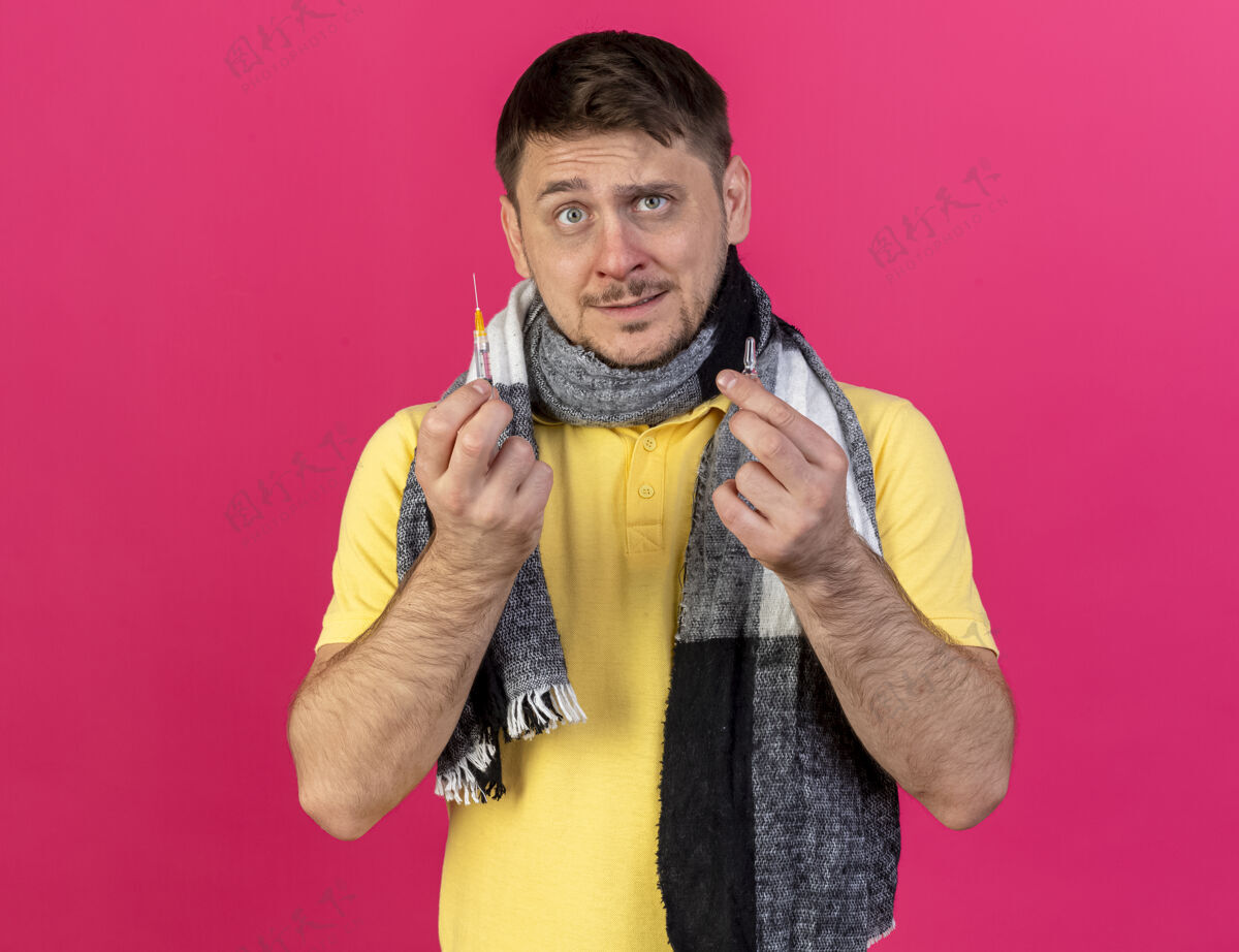 穿焦急的年轻金发病斯拉夫男子戴围巾持有注射器和安瓿对粉红色安瓿疾病围巾