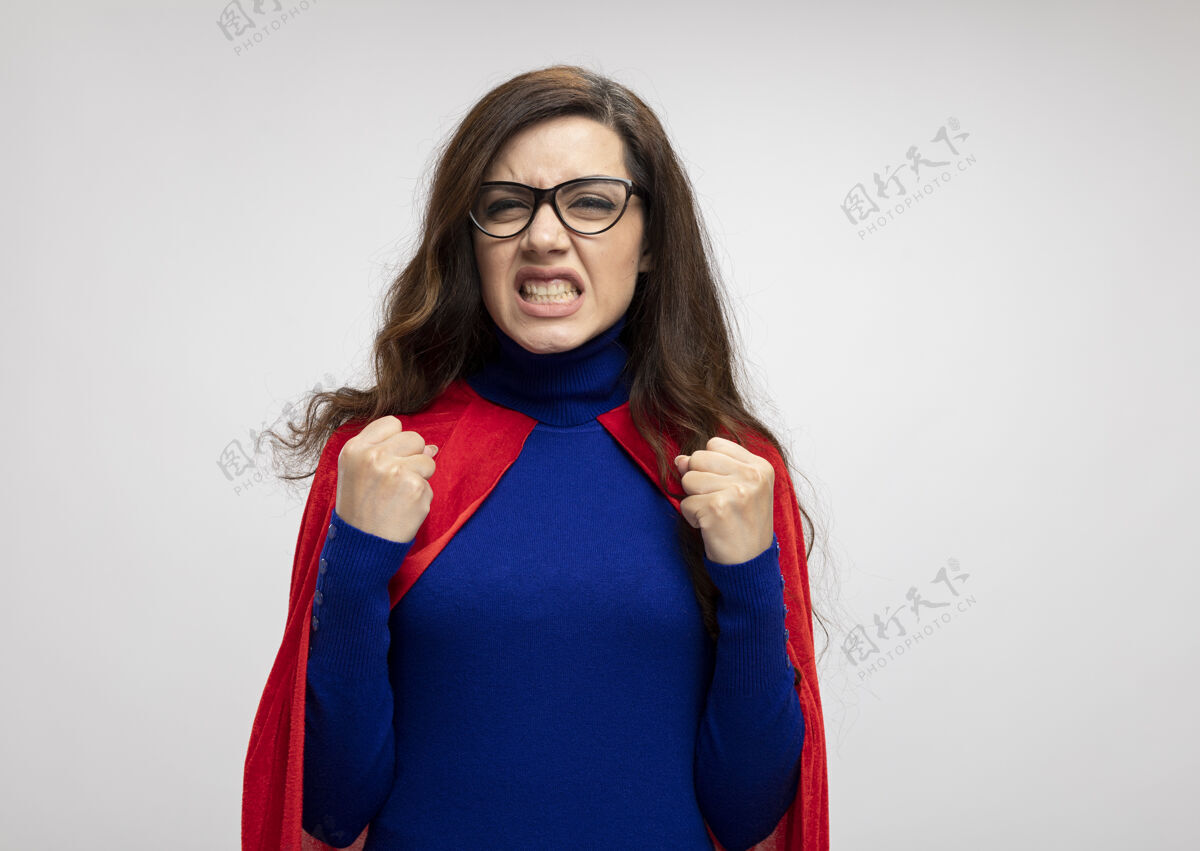 斗篷恼怒的白种人超级英雄女孩 戴着眼镜 披着红色斗篷 拳头紧握着白色光学眼镜超级英雄