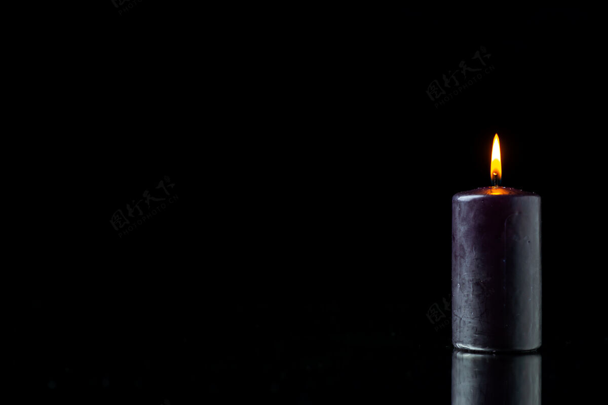 死亡黑暗表面上的黑暗蜡烛照明的前视图光黑燃烧