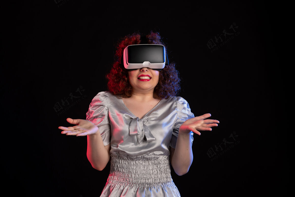 成人美丽的女性戴着虚拟现实耳机在黑暗的表面游戏姿势虚拟