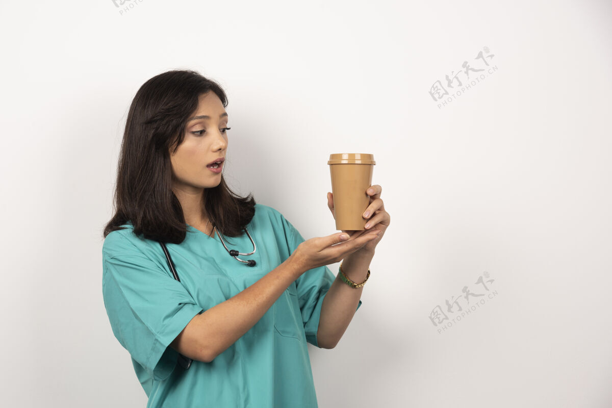 工作女医生用听诊器看白色背景上的咖啡高质量的照片杯子工人咖啡