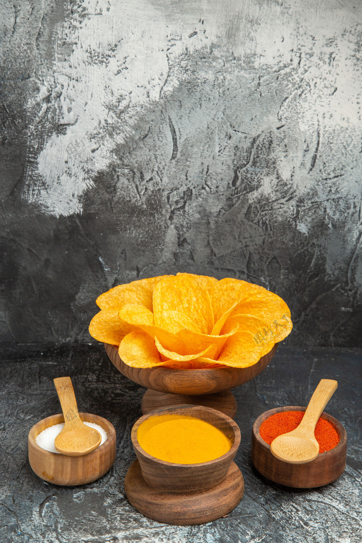果汁灰色桌子上装饰成花朵形状和不同香料的脆皮薯片的垂直视图鲜花食品香料