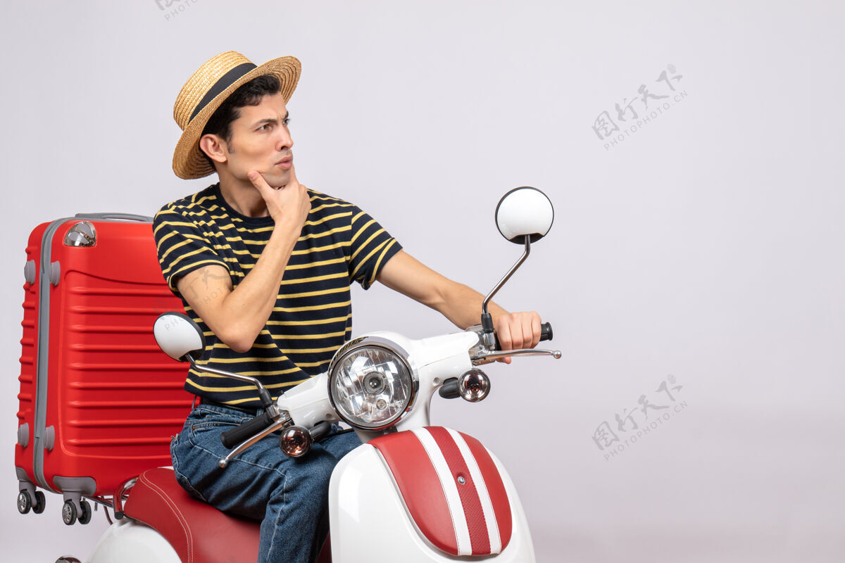 轻便摩托车一个体贴的年轻人 戴着草帽 坐在轻便摩托车上视图传送带成人