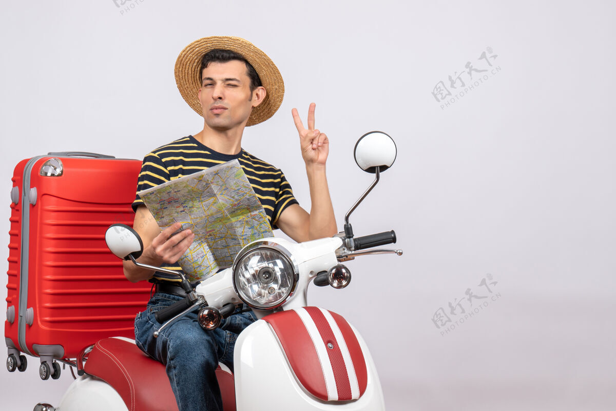 轻便摩托车一个戴着草帽的年轻帅哥在摩托车上做着胜利的手势视图帽子成人