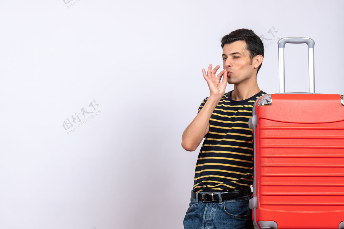 年轻人正面图：一个穿着条纹t恤和红色手提箱的年轻人在做美味的招牌微笑手提箱正面