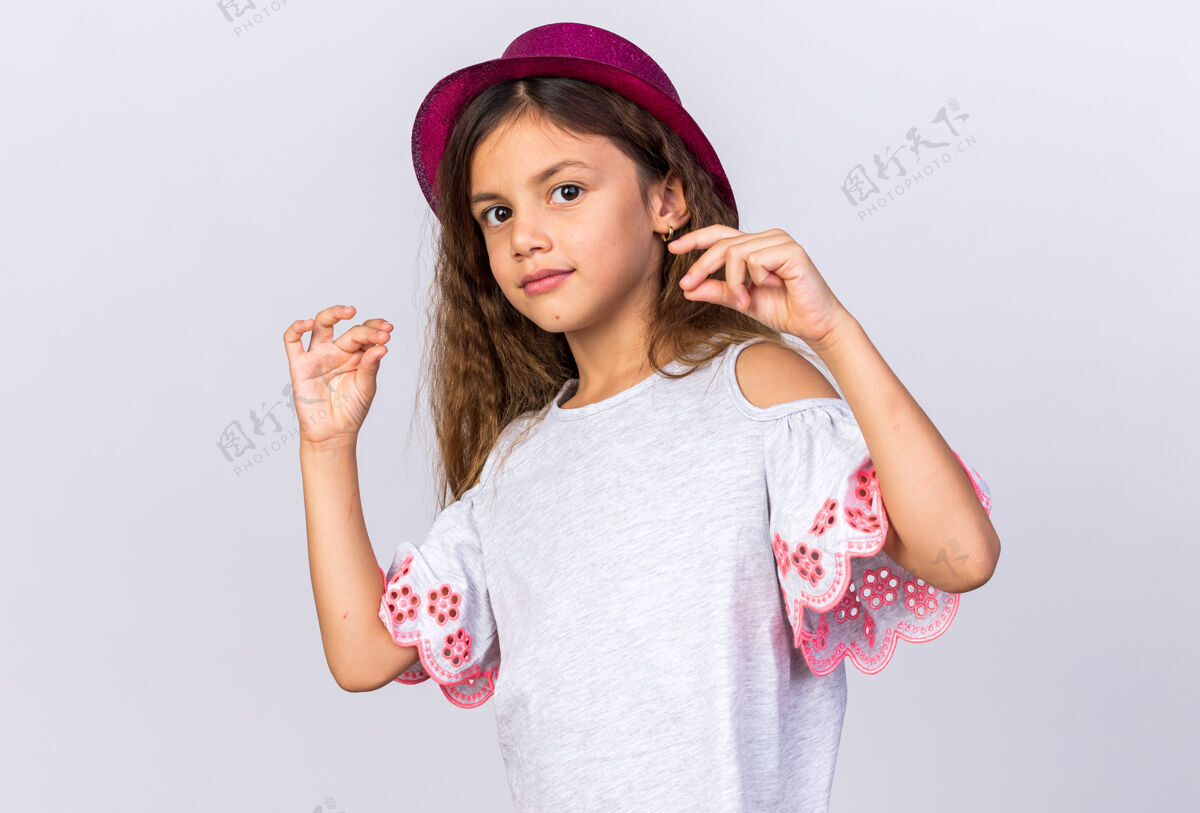 小的戴着紫色派对帽的可爱的白人小女孩假装拿着一个孤立的东西放在白色的墙上 留着复制空间东西生日帽子