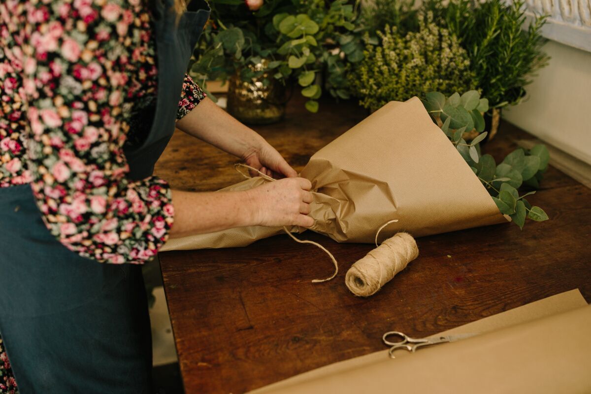 手欧洲女花匠带着绿色围裙在花卉工作室里插花人自然女人