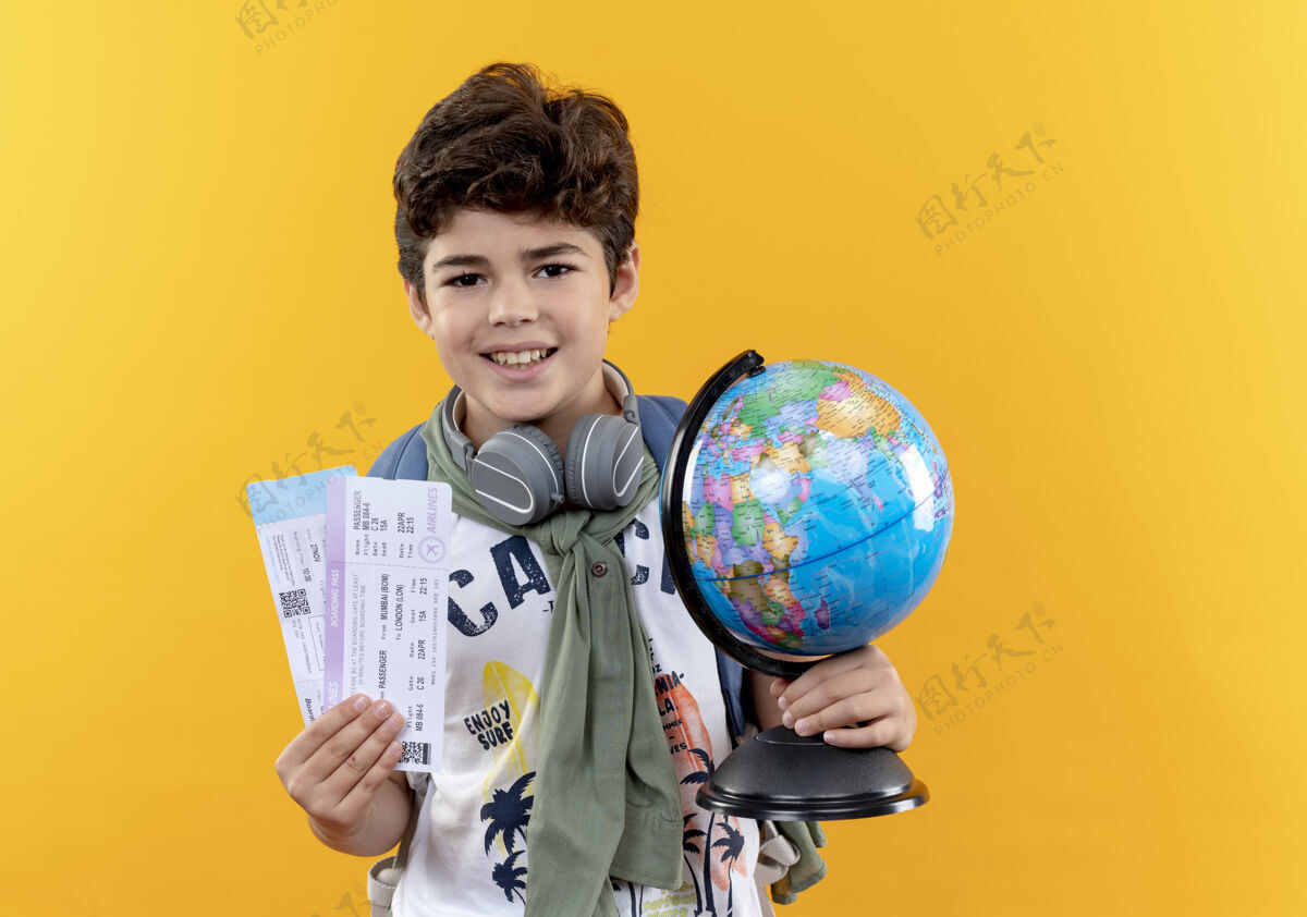 举行微笑着的小男孩 背着书包 戴着耳机 手里拿着票和地球仪微笑学校耳机