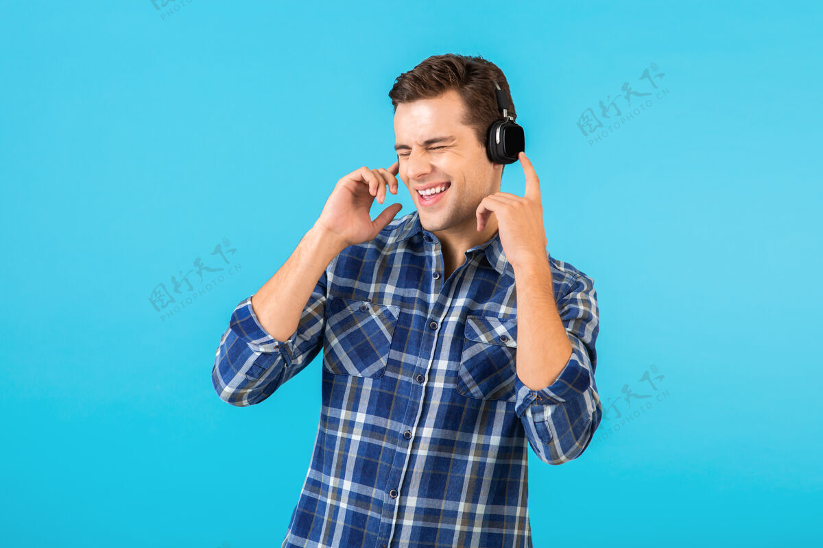 耳机坐在蓝色耳机上听音乐的男人的画像积极家伙娱乐