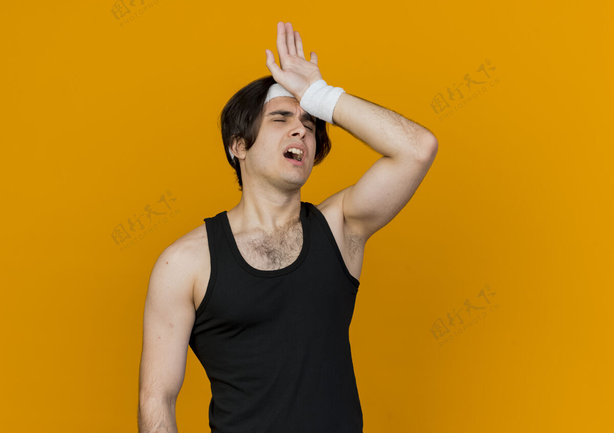 表情年轻的运动型男子穿着运动服和头带 站在橘色的墙上锻炼后显得疲惫和疲惫疲惫头带市民