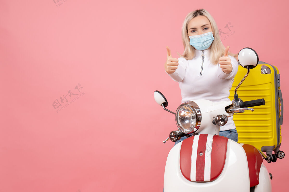 女士前视图：骑着轻便摩托车的年轻女士拿着黄色手提箱竖起大拇指手提箱前面制造