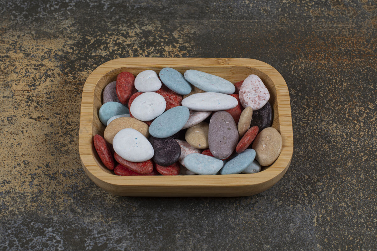 甜点木制盘子上的椭圆形石头糖果五彩岩石石头