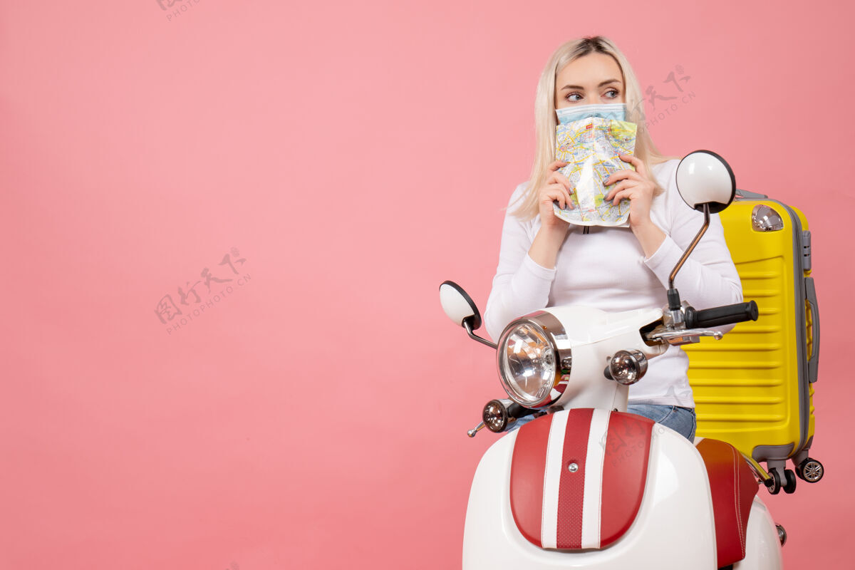 小姐前视图：骑着轻便摩托车的年轻女士 带着黄色手提箱 拿着免费的地图空间货柜摩托车地图