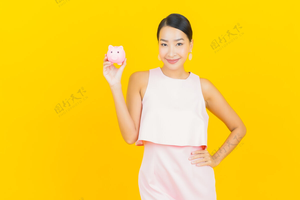 投资画一个漂亮的亚洲年轻女子 黄色的小猪存钱罐小猪银行亚洲人黄色