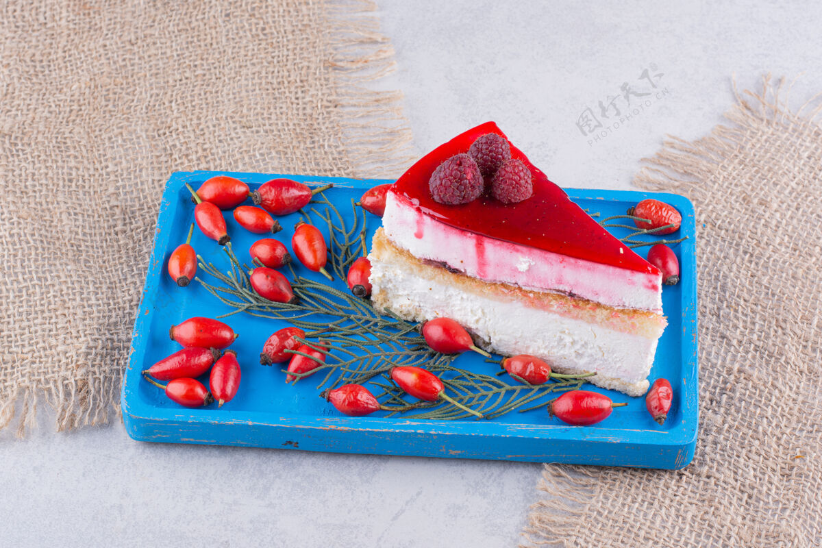 面包房蓝色盘子上放一片芝士蛋糕和新鲜的玫瑰果蛋糕水果美味