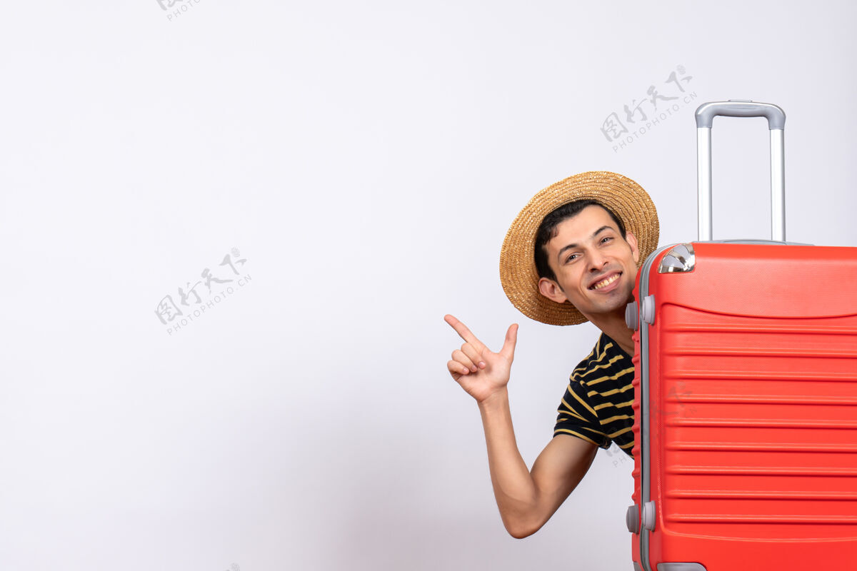 前面正面图：一个戴草帽的年轻人站在红色手提箱后面 指着什么东西吸管年轻人微笑