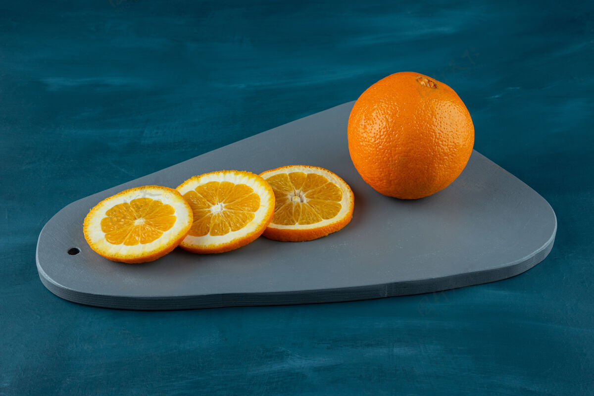 营养在蓝色的表面上放着切成片的多汁橙子的木板异国情调食品多汁