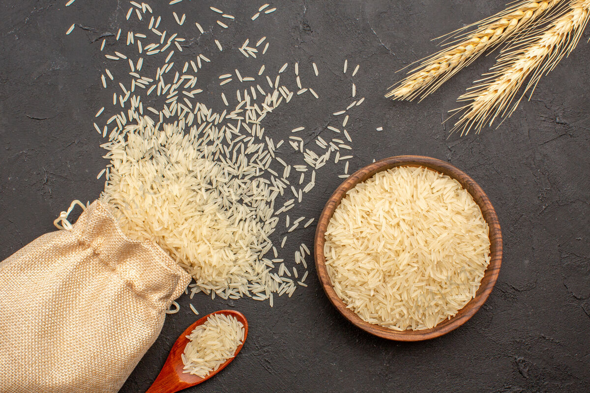 谷物在灰色表面上的袋子和盘子里的生米俯视图有机小麦袋子