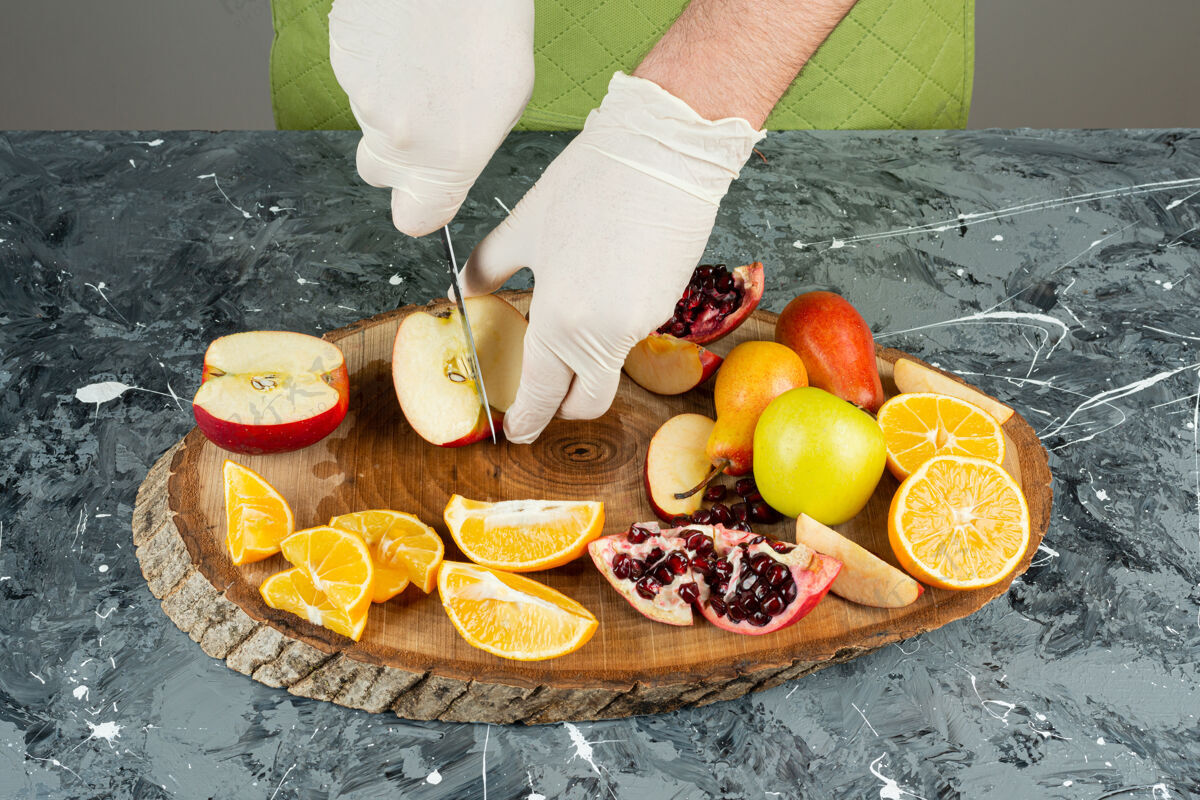 橙子男性手切新鲜的红苹果在大理石桌上切石榴混合