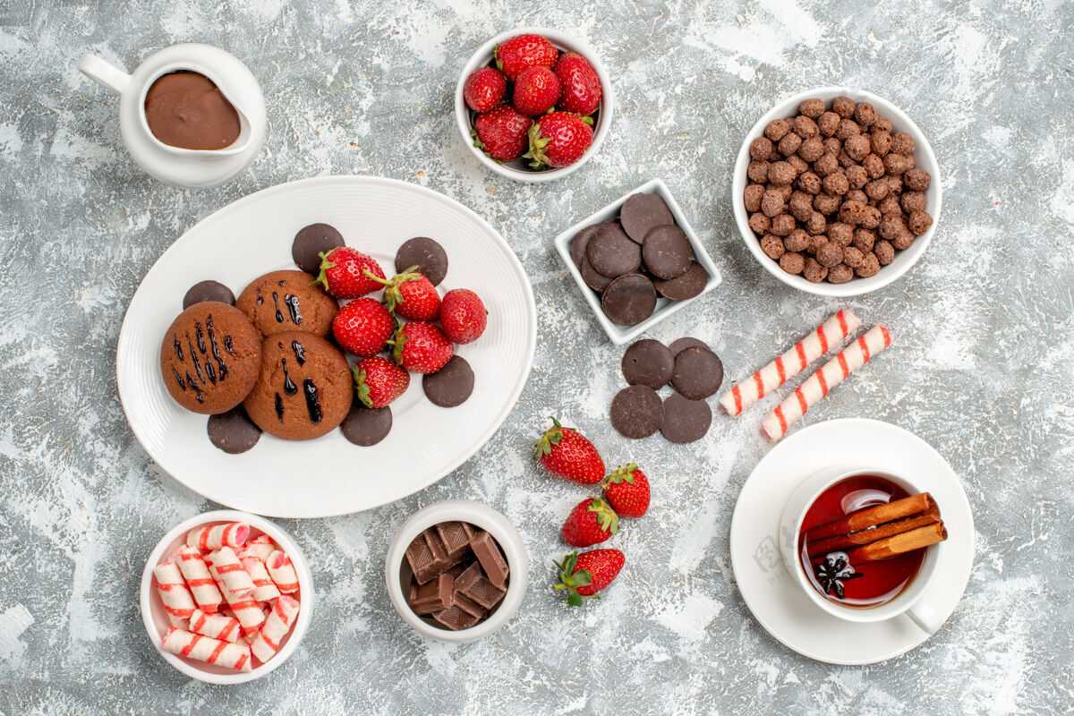 研磨顶视图碗里有糖果草莓巧克力谷类糖果可可和一些草莓糖果巧克力和一杯茶在灰白色的地面上新鲜糖果茶