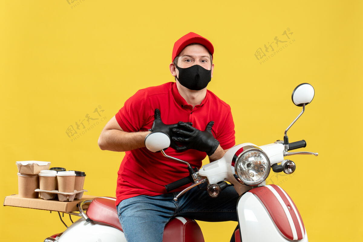 摩托车谢天谢地的快递员身穿红色上衣 戴着帽子手套 戴着医用面罩 坐在滑板车上传递订单交付面罩医疗