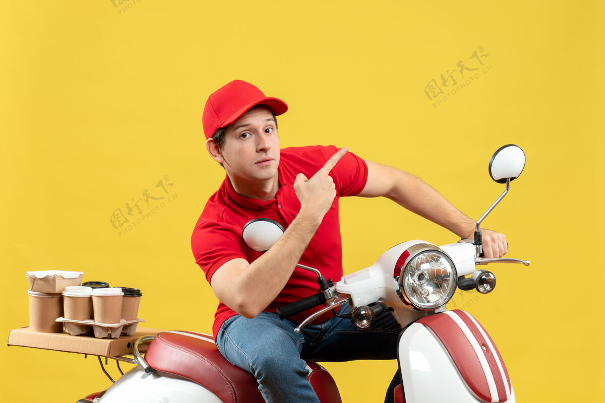 黄色穿着红色上衣 戴着帽子 在黄色背景上向上传递命令的惊讶的年轻人的正面视图年轻人运动车辆