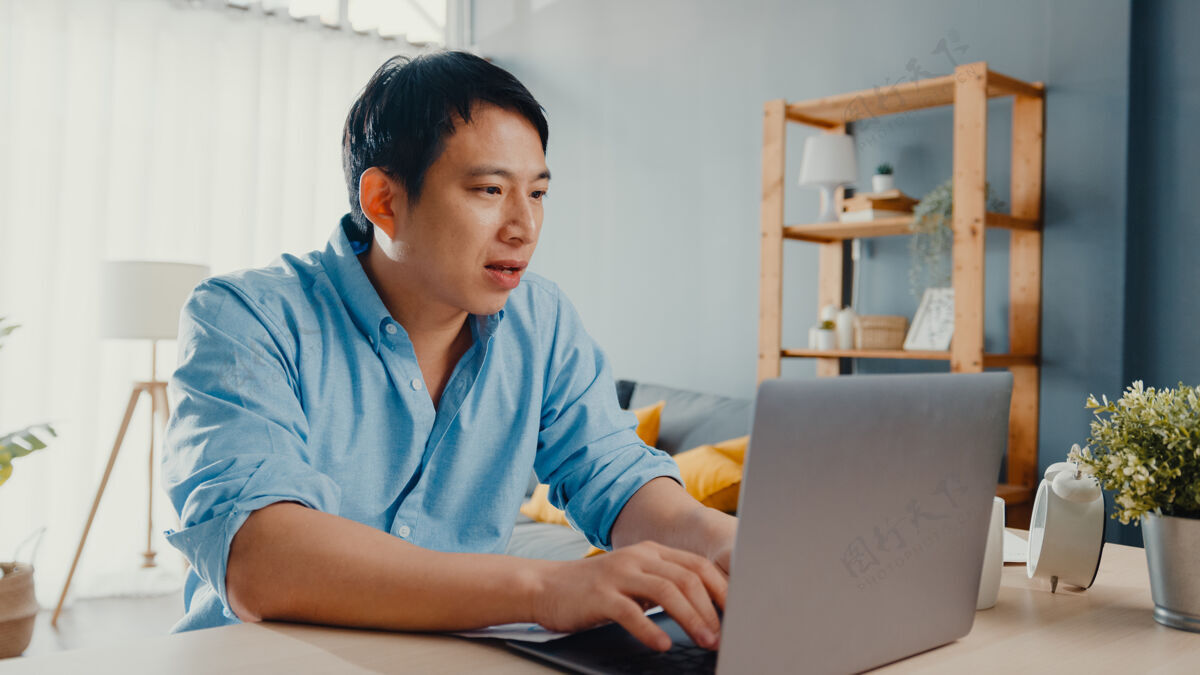 压力自由亚洲家伙休闲服使用笔记本电脑在线客厅在家办公企业家办公桌视频
