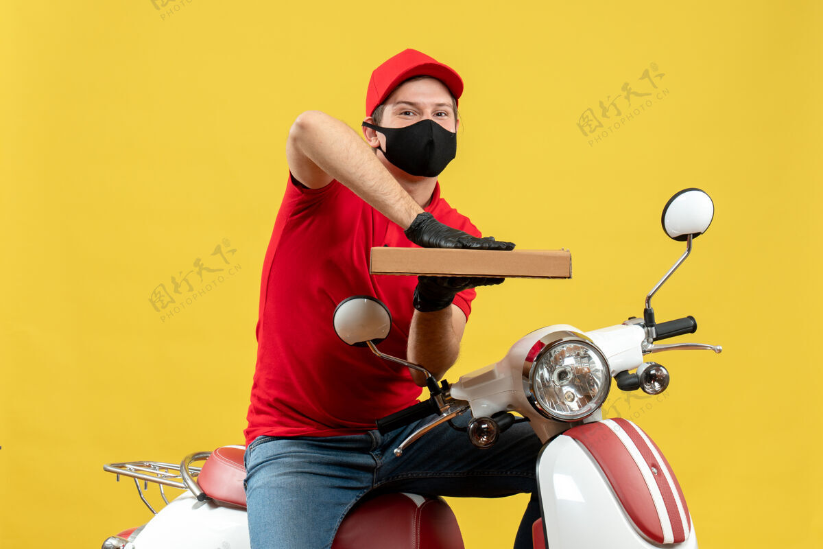 帽子上图是一个穿着红色上衣 戴着帽子手套 戴着医用口罩 坐在滑板车上显示秩序的快乐满意的快递员车辆命令手套