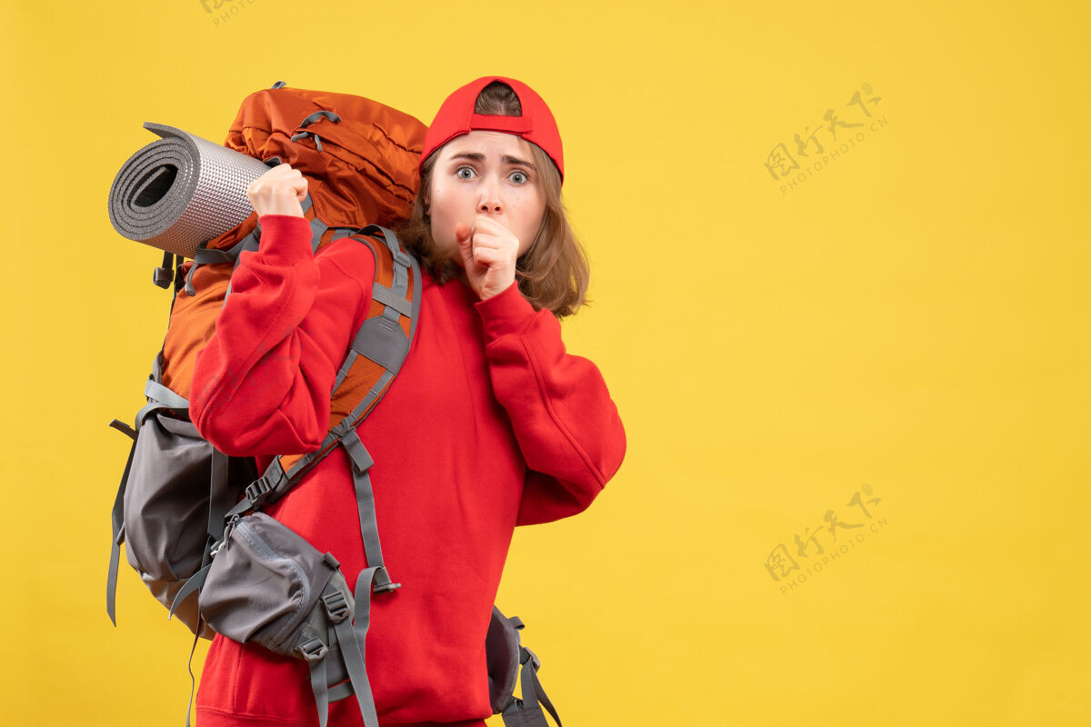 帽子前视图困惑的旅行者妇女在红色背包站在黄色的墙上背包站工作