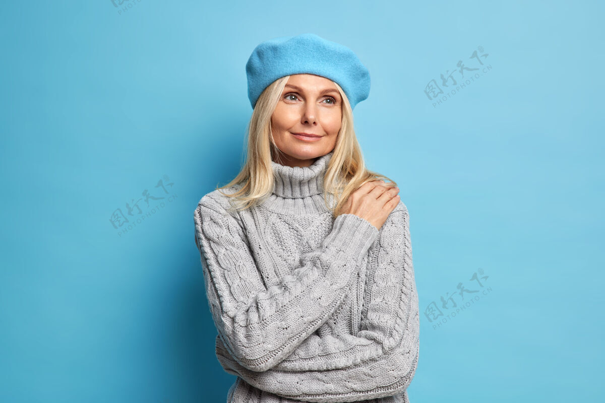灰色喜出望外的欧洲金发女人有着温柔满足的表情 头戴贝雷帽 穿着针织套头衫 神情凝重 神情沉思微笑表情中间