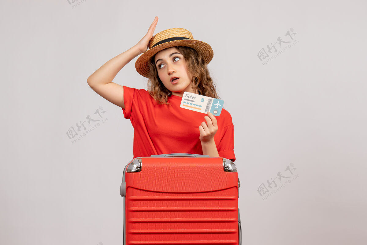 青年困惑的度假女孩正拿着她的旅行箱 手里拿着票人欢呼漂亮