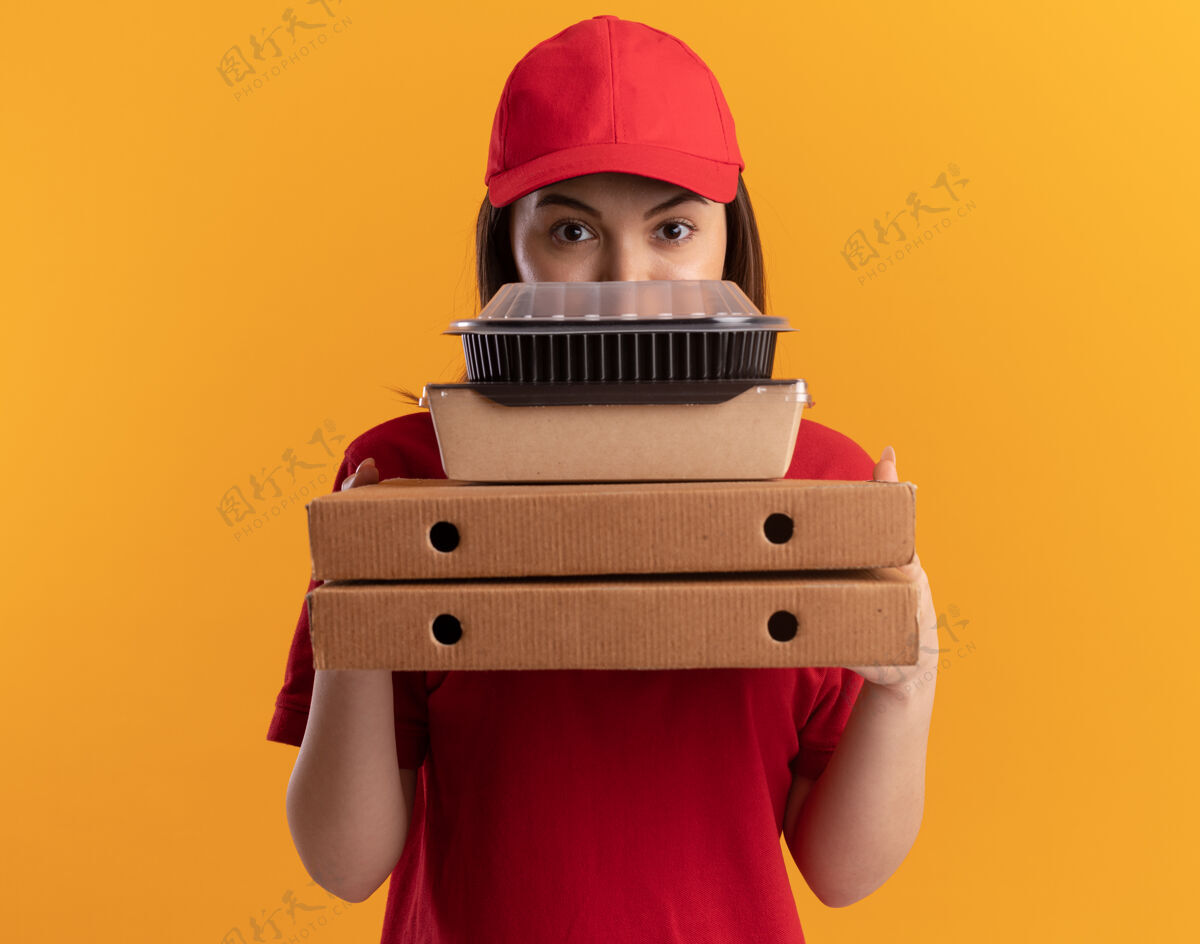送货自信漂亮的女送货员穿着制服拿着纸食品包装的比萨饼盒上的橙色食物女人漂亮