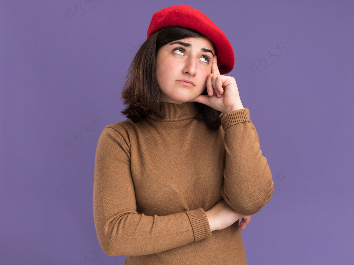 失望失望的年轻漂亮白人女孩戴着贝雷帽 把手放在太阳穴上 抬头看着紫色漂亮帽子太阳穴
