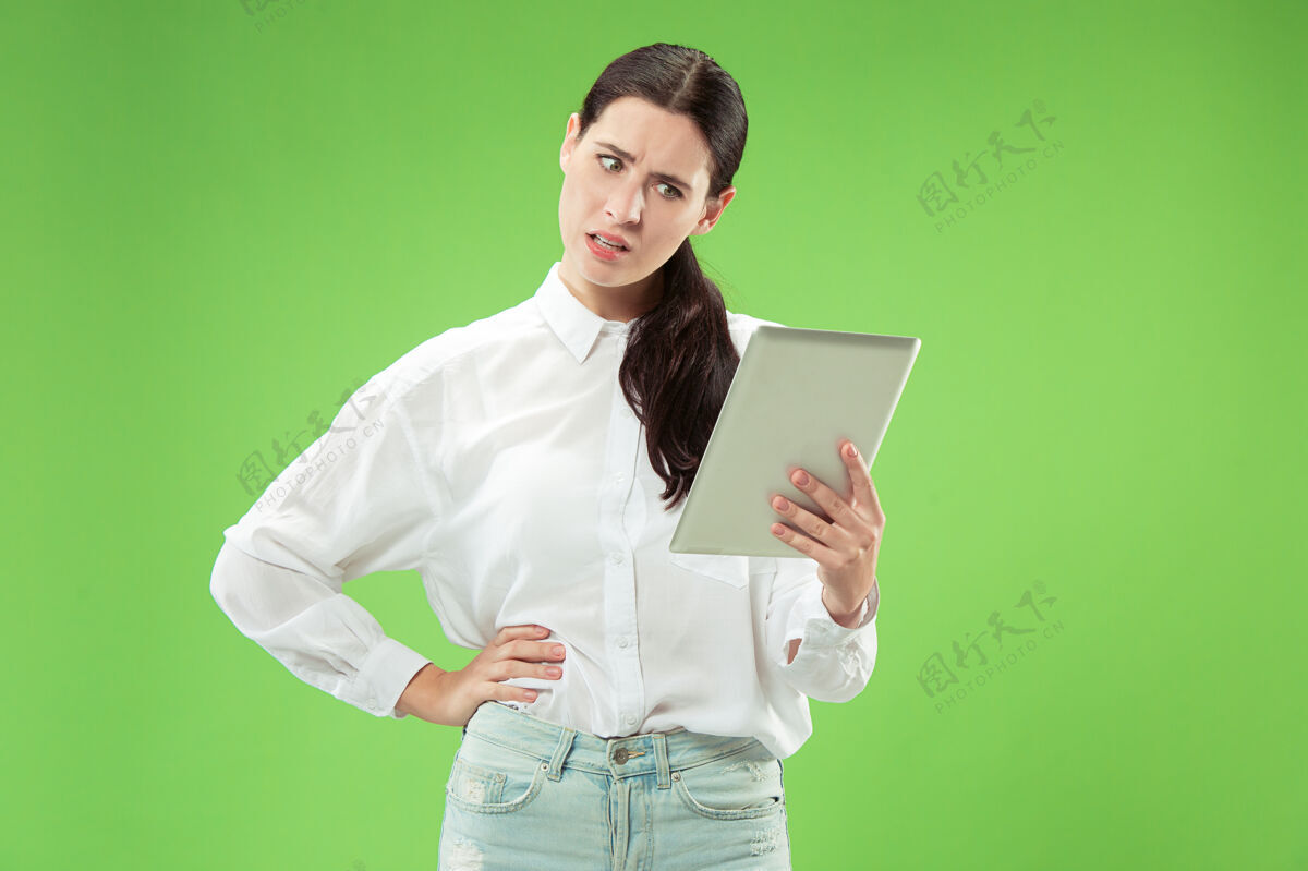 女性带笔记本电脑的女商人热爱电脑概念迷人的女性半身正面肖像 时尚的绿色工作室背景年轻感性的美女人类情感 面部表情肖像人脸