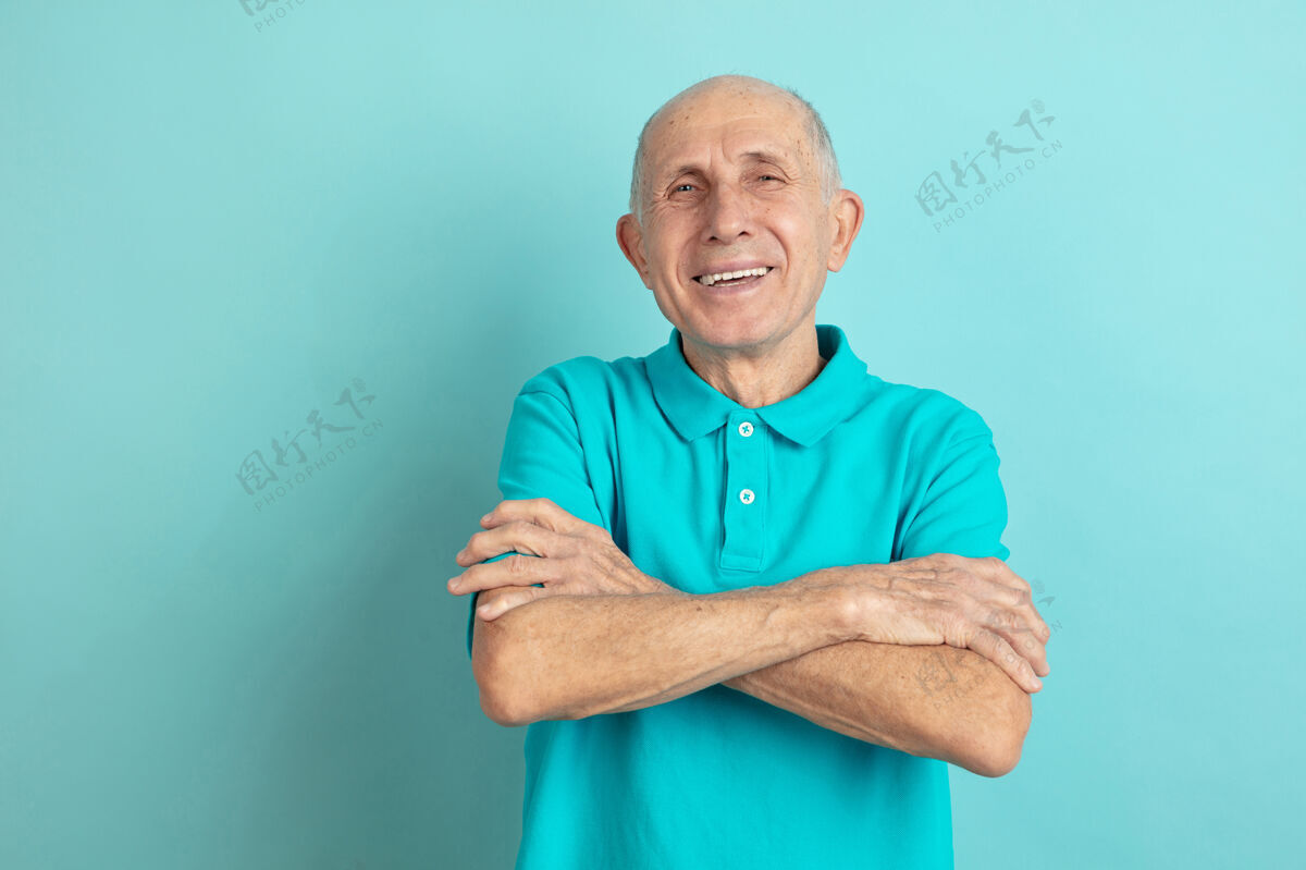 人双手交叉高加索老人的肖像隔离在蓝色的工作室背景上美丽的男性情感模型人类情感的概念 面部表情 销售 福利 广告空间衬衫财务手