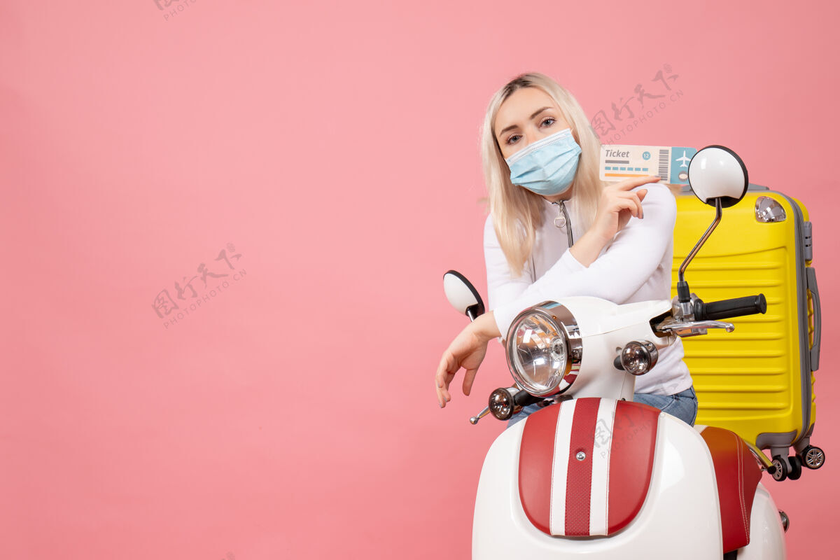 票正面图漂亮的年轻女士 骑着轻便摩托车 带着黄色手提箱 手里拿着机票轻便摩托车手提箱前面