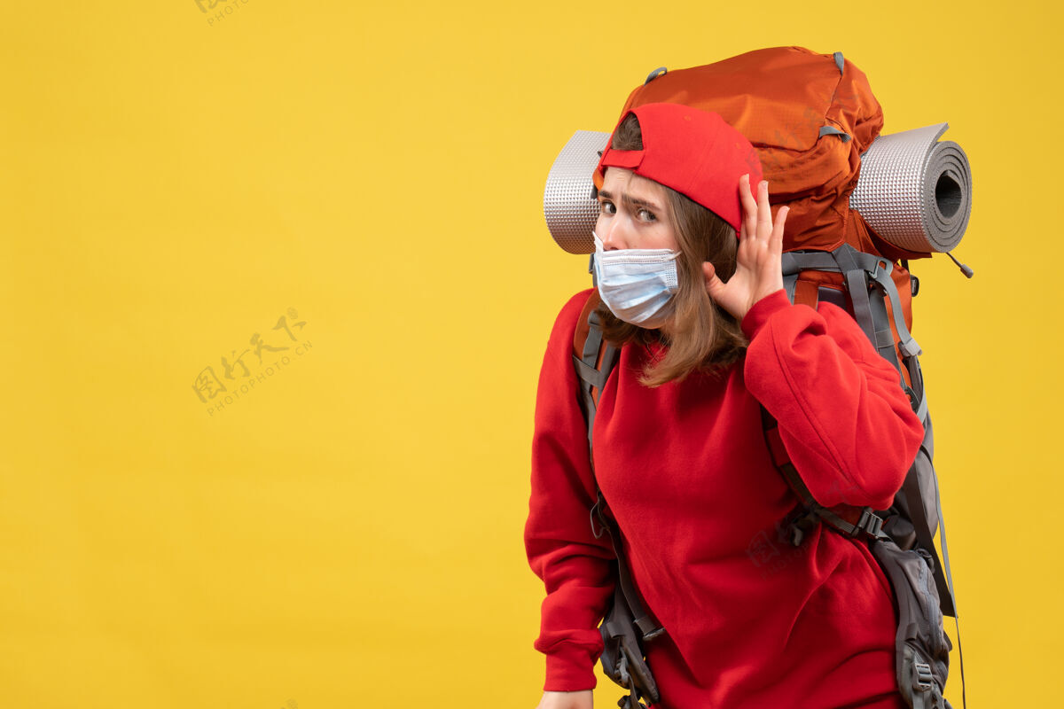 背包前视图好奇的年轻女孩带着旅游背包和面具在听什么快乐肖像面具