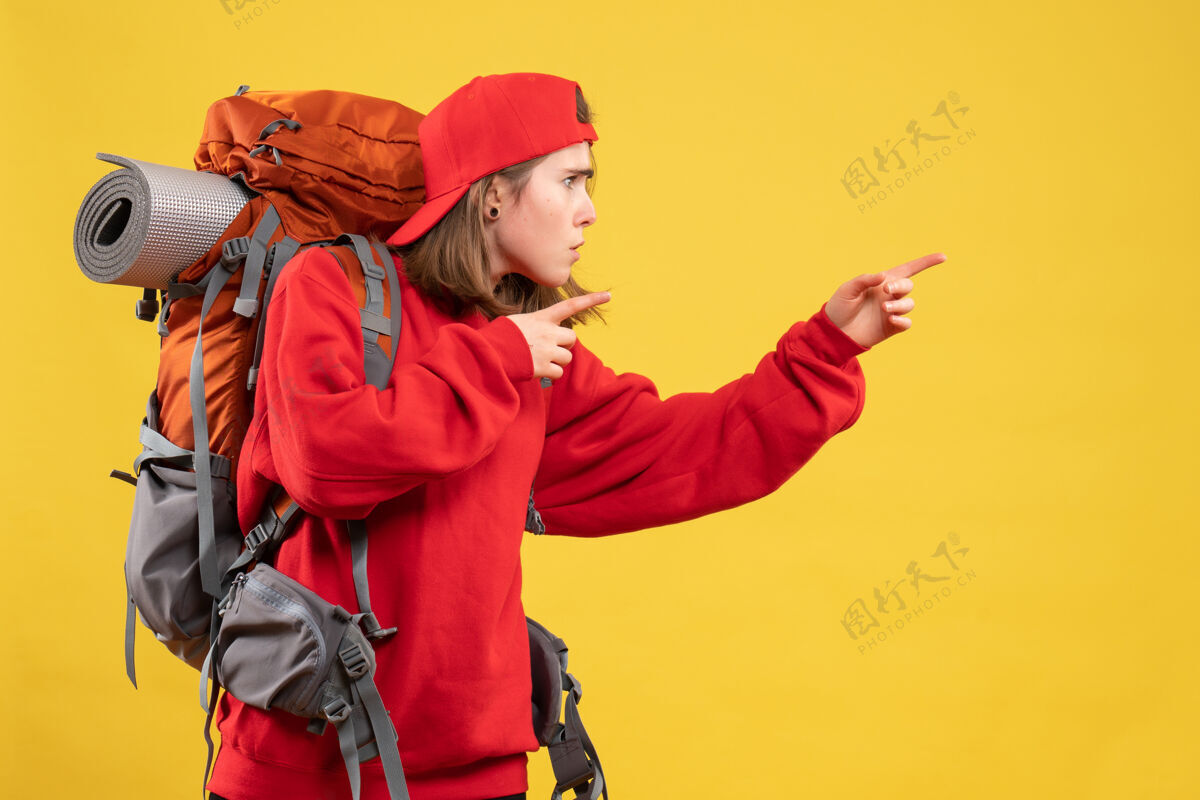 前面正面图很酷的女旅行者 背着背包 手指指向右边人头盔成人