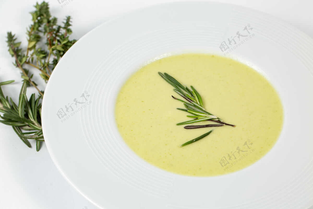 美食在一张装饰着绿色植物的白色桌子上 拍下了一盘西葫芦奶油汤汤烹饪餐具