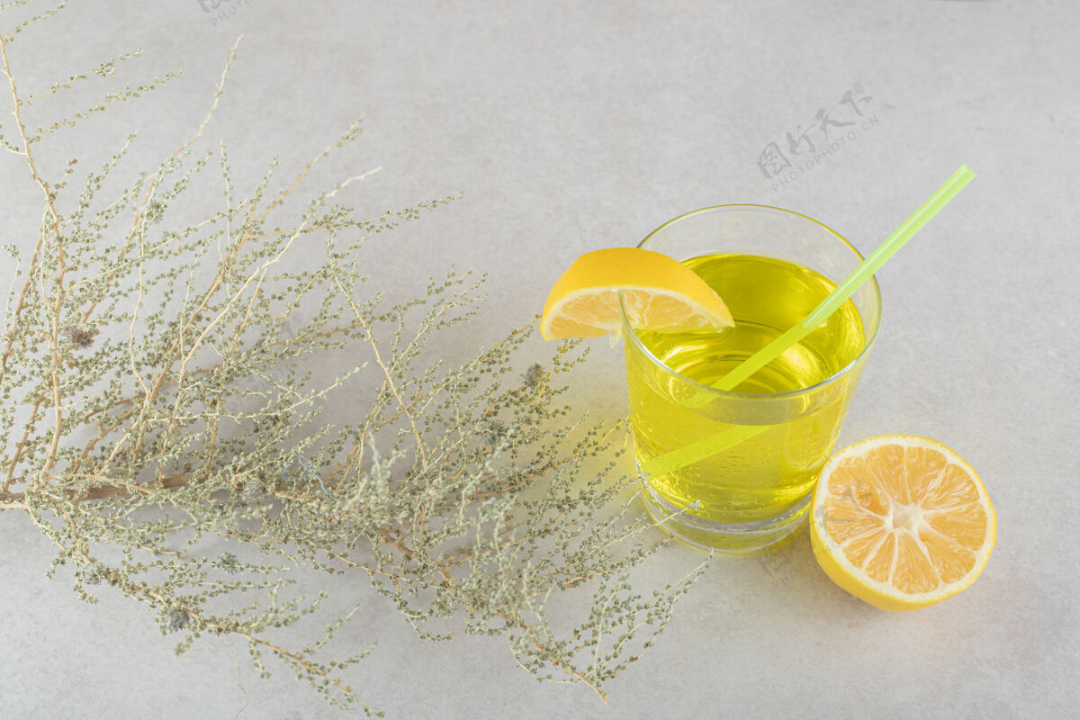 玻璃一杯柠檬水 柠檬和稻草放在灰色的表面上柠檬膳食水果