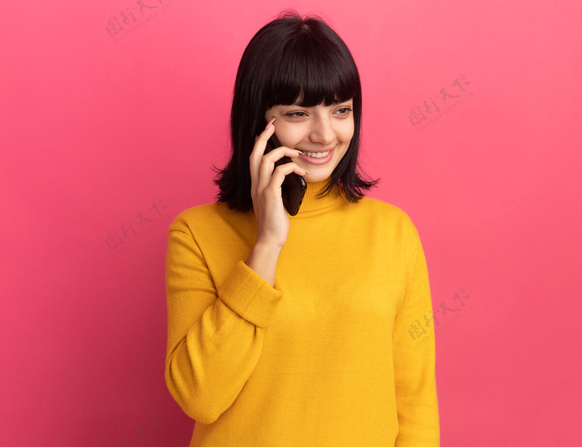侧线高兴的年轻黑发高加索人女孩在电话里看着粉红色的一面黑发拜托杨