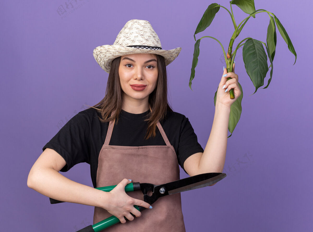 花园自信漂亮的白人女园丁戴着园艺帽手持园艺剪刀和紫色的植物枝剪刀漂亮帽子