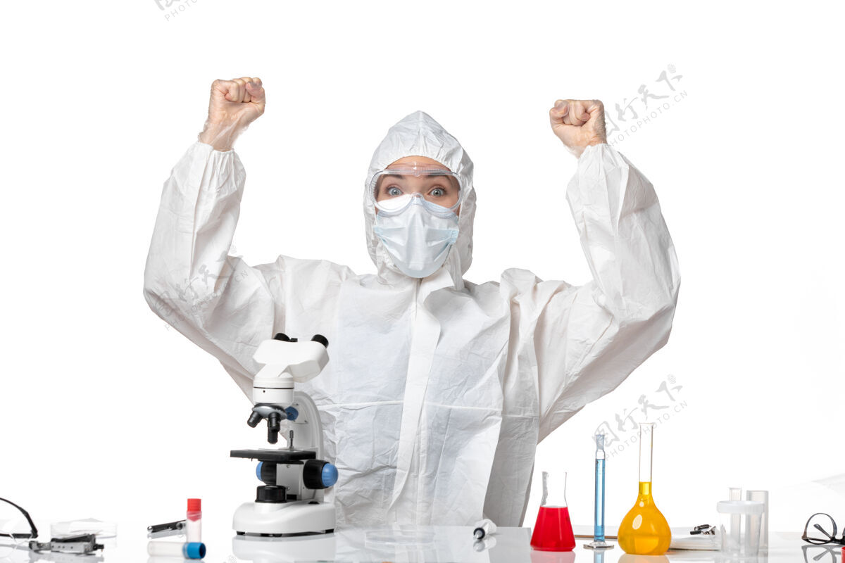 实验室外套正面图：女医生穿着防护服 戴着口罩 因为白色办公桌上有病毒大流行 溅起了病毒办公桌正面男子